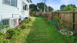 A residential backyard with a lawn, a wooden fence, and various plants. - Ekhaya - New Plymouth Holiday Home (New Plymouth)