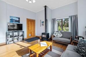 Una sala de estar moderna con televisor, muebles de madera, chimenea y un ventanal grande.