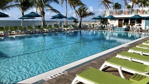 Ein Swimmingpool mit Liegestühlen und Sonnenschirmen, umgeben von Palmen.