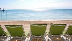 A beach with three green lounge chairs facing the ocean.