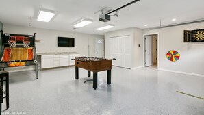 A spacious room with a foosball table, a basketball hoop, and a dartboard. - Recently Updated 3 Bedroom House, Fire Pit, Hot Tub, Game Room (New Buffalo)