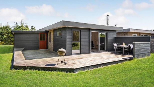 Una casa moderna con una terraza, una parrilla y una mesa de patio.