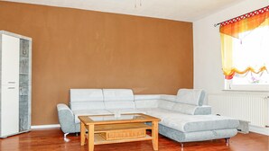 A living room with a sectional sofa, a wooden coffee table, a ceiling fan, and a window with a curtain. - Nice home in Kalbe/ Milde -Kakerbec with WiFi (Kalbe/ Milde -Kakerbec)