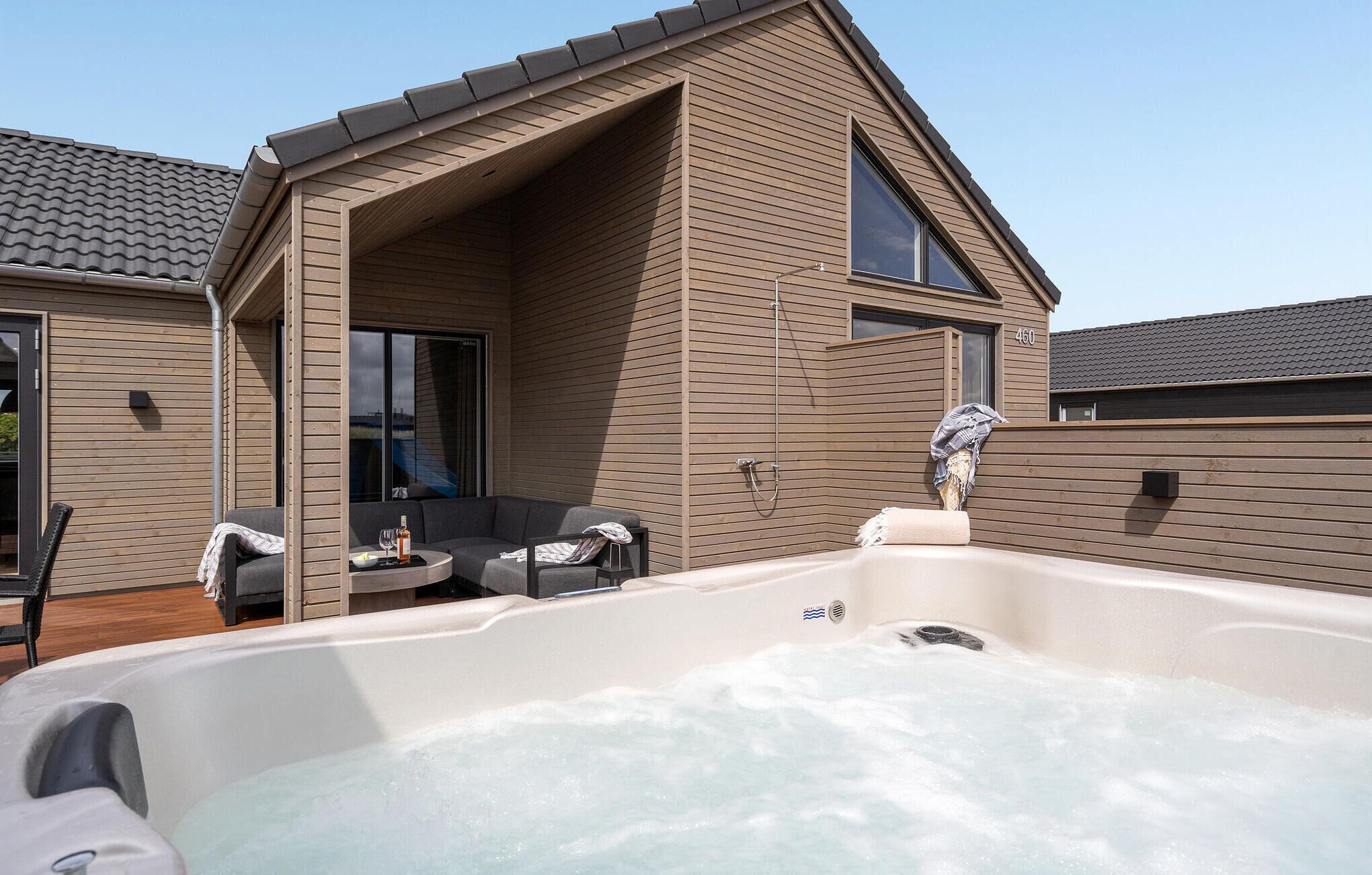 A modern house with a hot tub, a covered patio, and a large window.