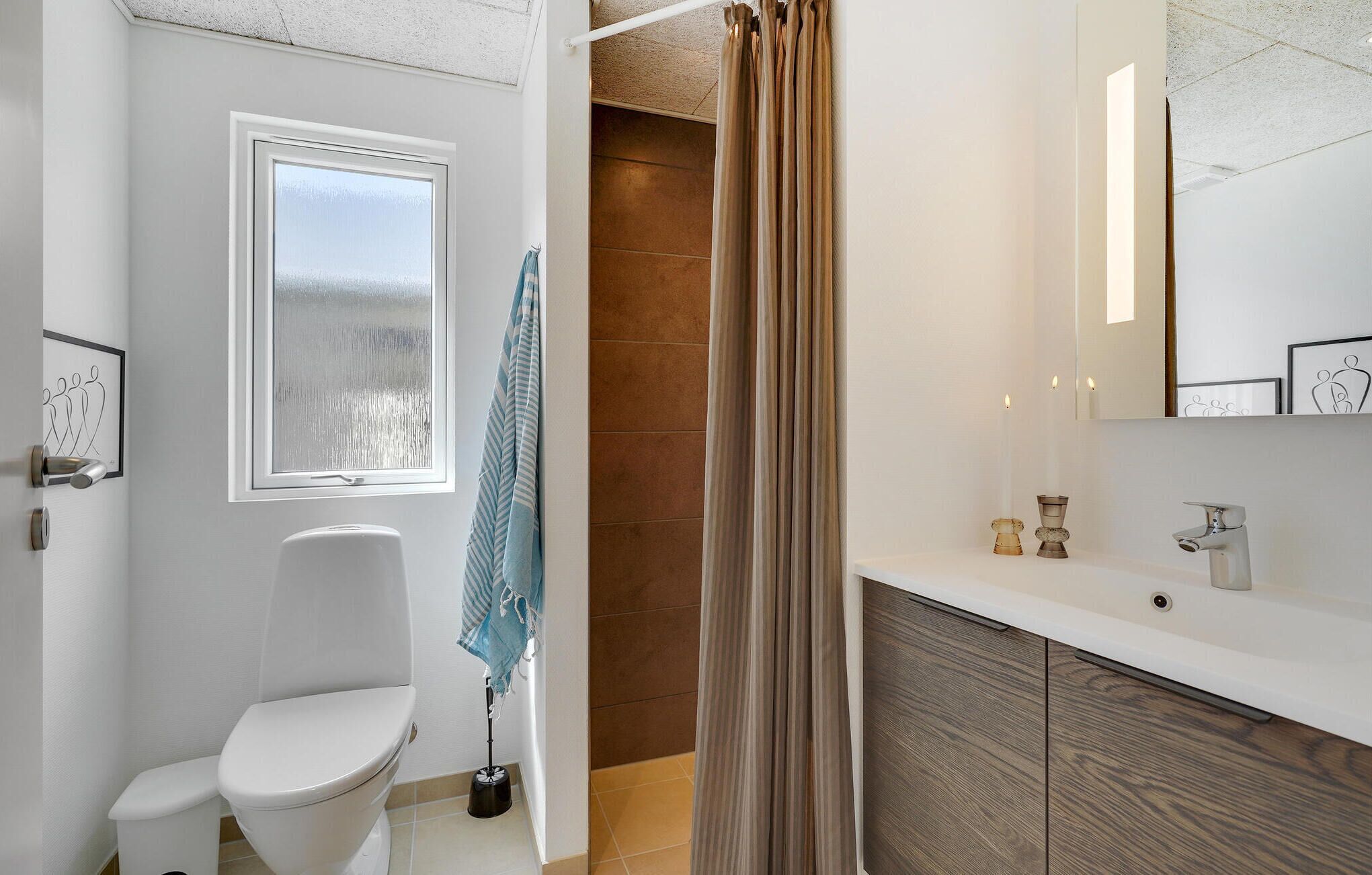 Une salle de bain moderne avec des toilettes, un rideau de douche, un lavabo avec un miroir et une serviette accrochée au mur.