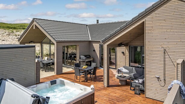 Un espace de vie extérieur moderne comprenant un jacuzzi, une table à manger et des sièges.
