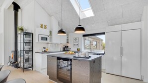 Une cuisine moderne dotée d’un îlot central, de meubles blancs et d’une verrière.