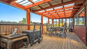 A covered outdoor deck with a wooden floor, a table with chairs, a grill, and a telescope. - 3 bedroom lovely home in Karrebæksminde (Karrebæksminde)
