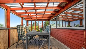 An outdoor patio with a wooden table and chairs, a glass ceiling, and a view of the surrounding landscape. - 3 bedroom lovely home in Karrebæksminde (Karrebæksminde)