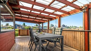 A covered patio with a wooden table and chairs, large windows, and a view of the neighborhood. - 3 bedroom lovely home in Karrebæksminde (Karrebæksminde)