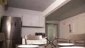 A modern kitchen with a built-in refrigerator, microwave, and white cabinets. There is a dining table with plates and cutlery, and a chair in the foreground. - Private Apartment close to everything you need! (San Juan)