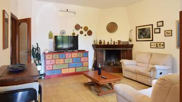 Ein Wohnzimmer mit Fernseher, Kamin, Sofa und Couchtisch.