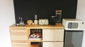 A compact kitchenette with a sink, toaster, coffee maker, and microwave. - VALLE LIFE (Valle de Guadalupe)