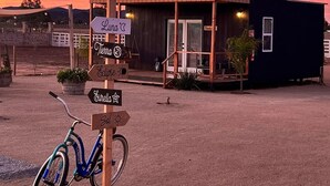 A rustic building with a wooden signpost indicating directions to various locations. - VALLE LIFE (Valle de Guadalupe)