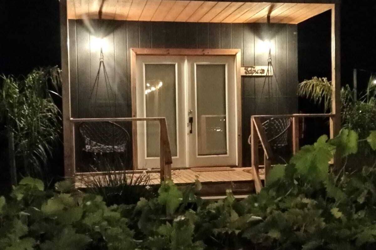 A small, dark wooden cabin with two glass doors and a wooden porch.