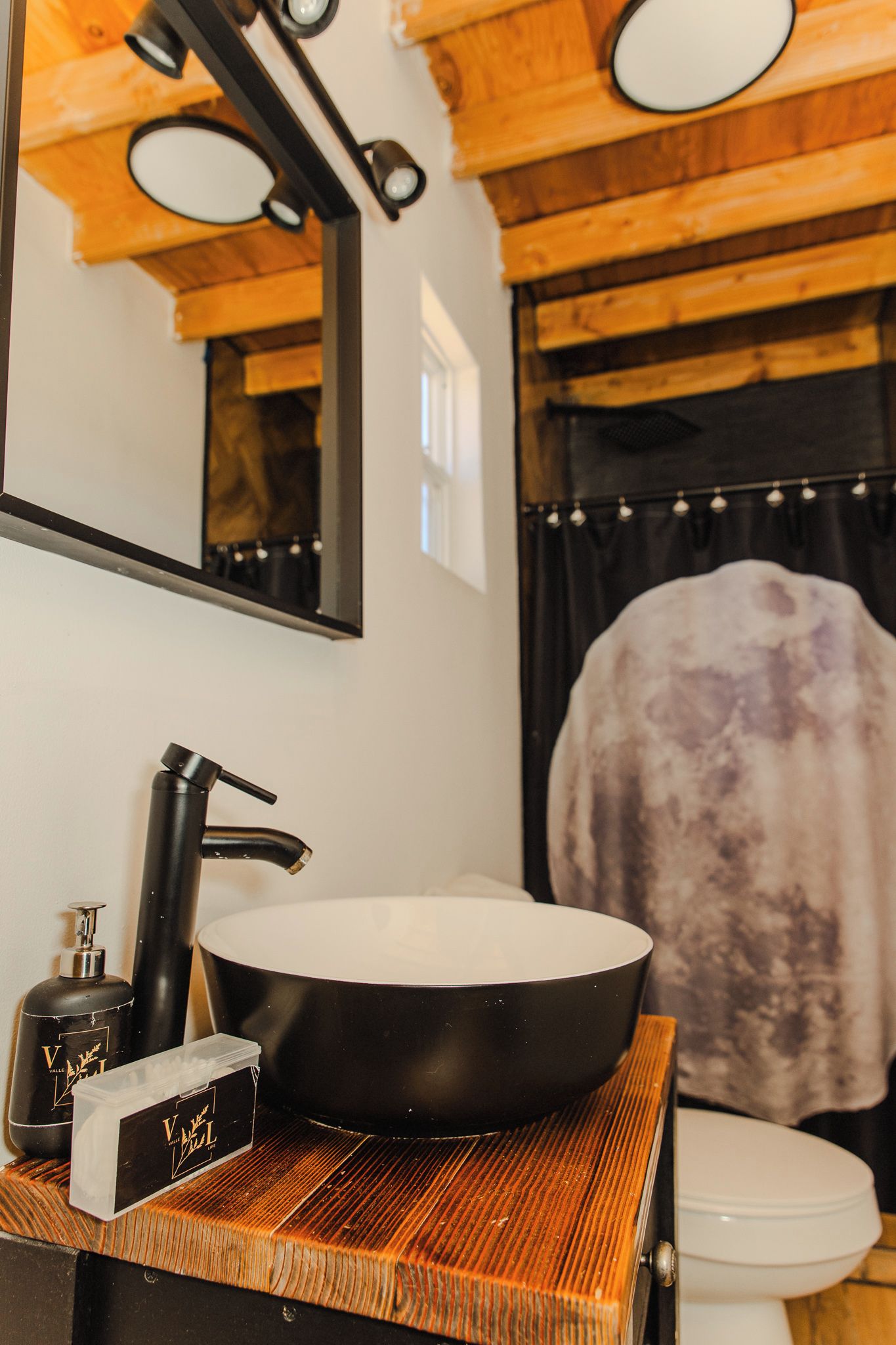 A bathroom with a wooden vanity, a large mirror, and a toilet.