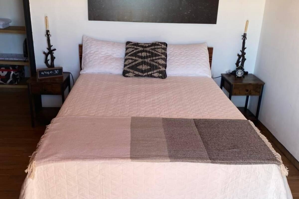 A bedroom with a bed, a nightstand, a wall clock, and a framed picture of the moon phases.