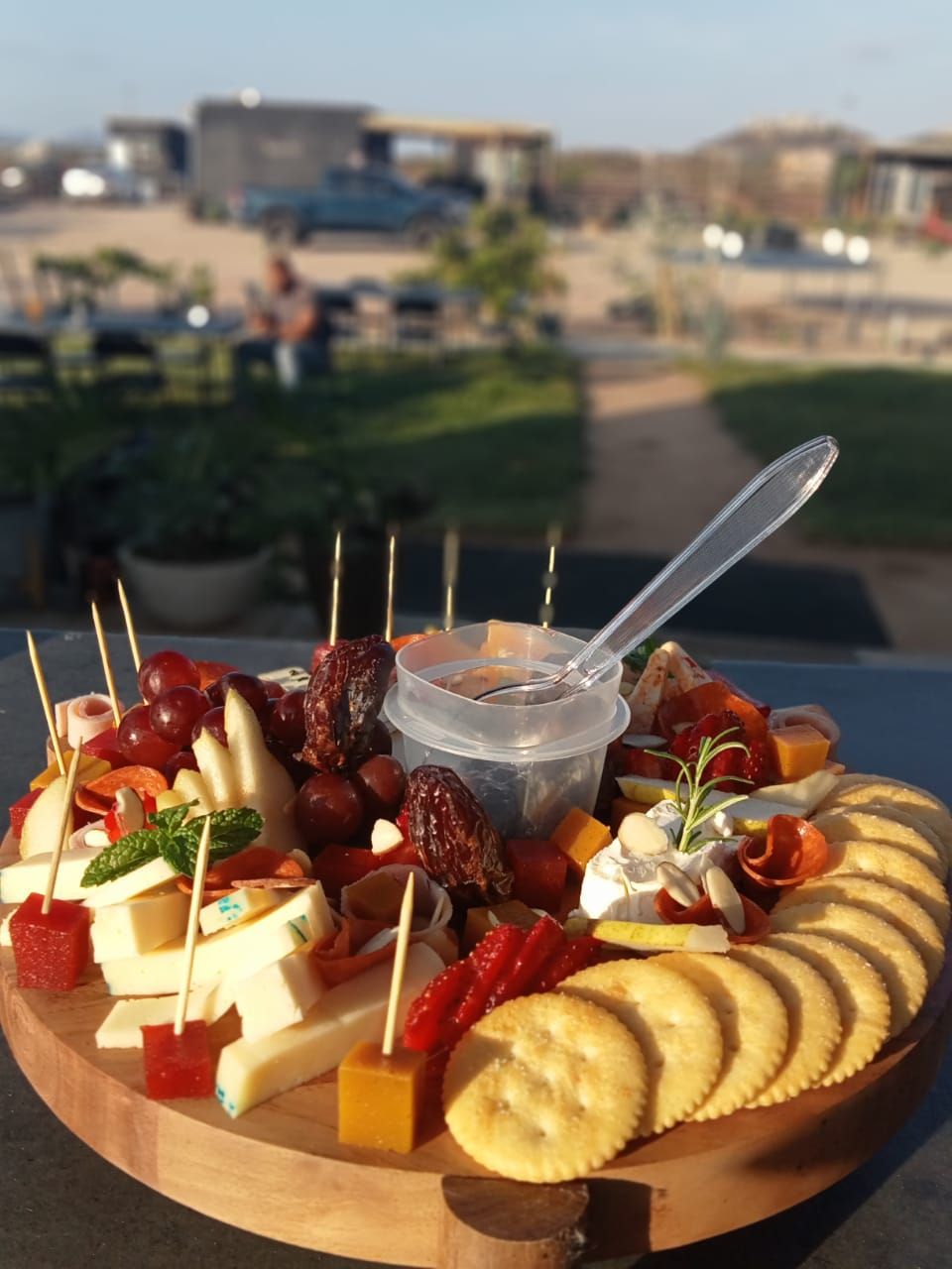 A charcuterie board with various cheeses, fruits, and crackers on a wooden board.