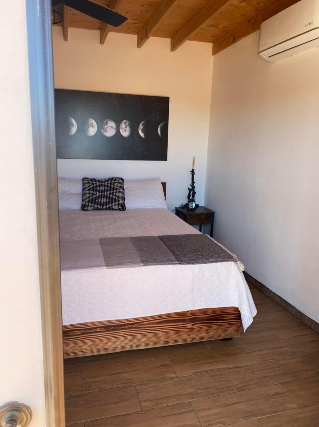 Une chambre à coucher avec un lit, un climatiseur fixé au mur et un plancher en bois.