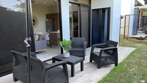 An outdoor patio with wicker furniture, a potted plant, and a sliding glass door leading to an interior space.