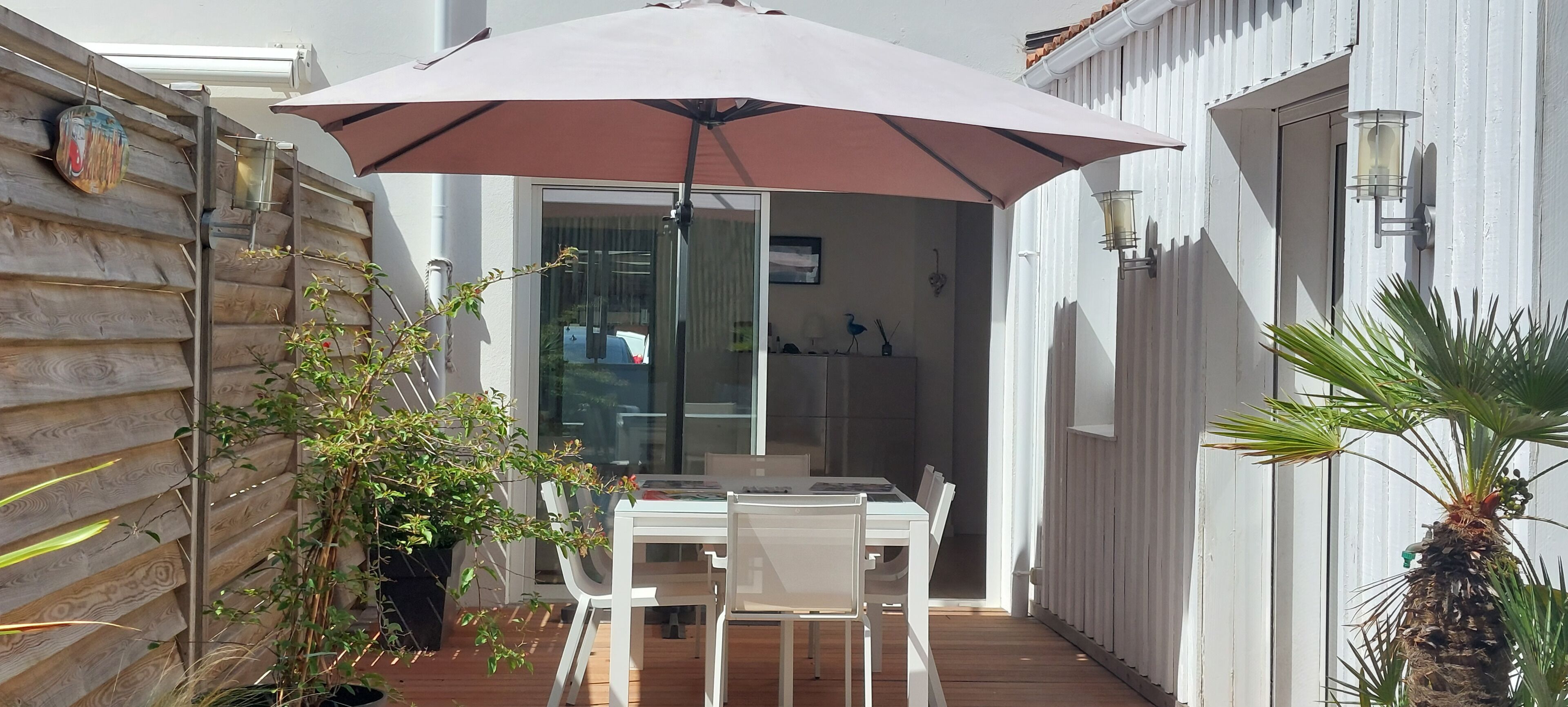 A patio with a table and chairs, an umbrella, and potted plants.