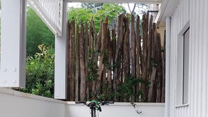 Un espace extérieur abrité doté d’un plancher en bois, d’un vélo et d’une clôture en bois ornée de plantes.