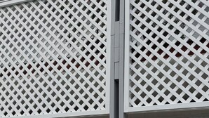 Un bâtiment à l’extérieur blanc, avec un toit gris et une clôture blanche en treillis.