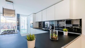 A modern kitchen with a black countertop, white cabinets, and a glass backsplash. There are two potted plants on the counter. - Cozy apartment in Lido di Camaiore with sauna (Lido di Camaiore)