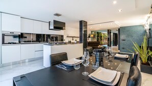 A modern kitchen with built-in appliances and a dining area with a black table set for six. - Cozy apartment in Lido di Camaiore with sauna (Lido di Camaiore)