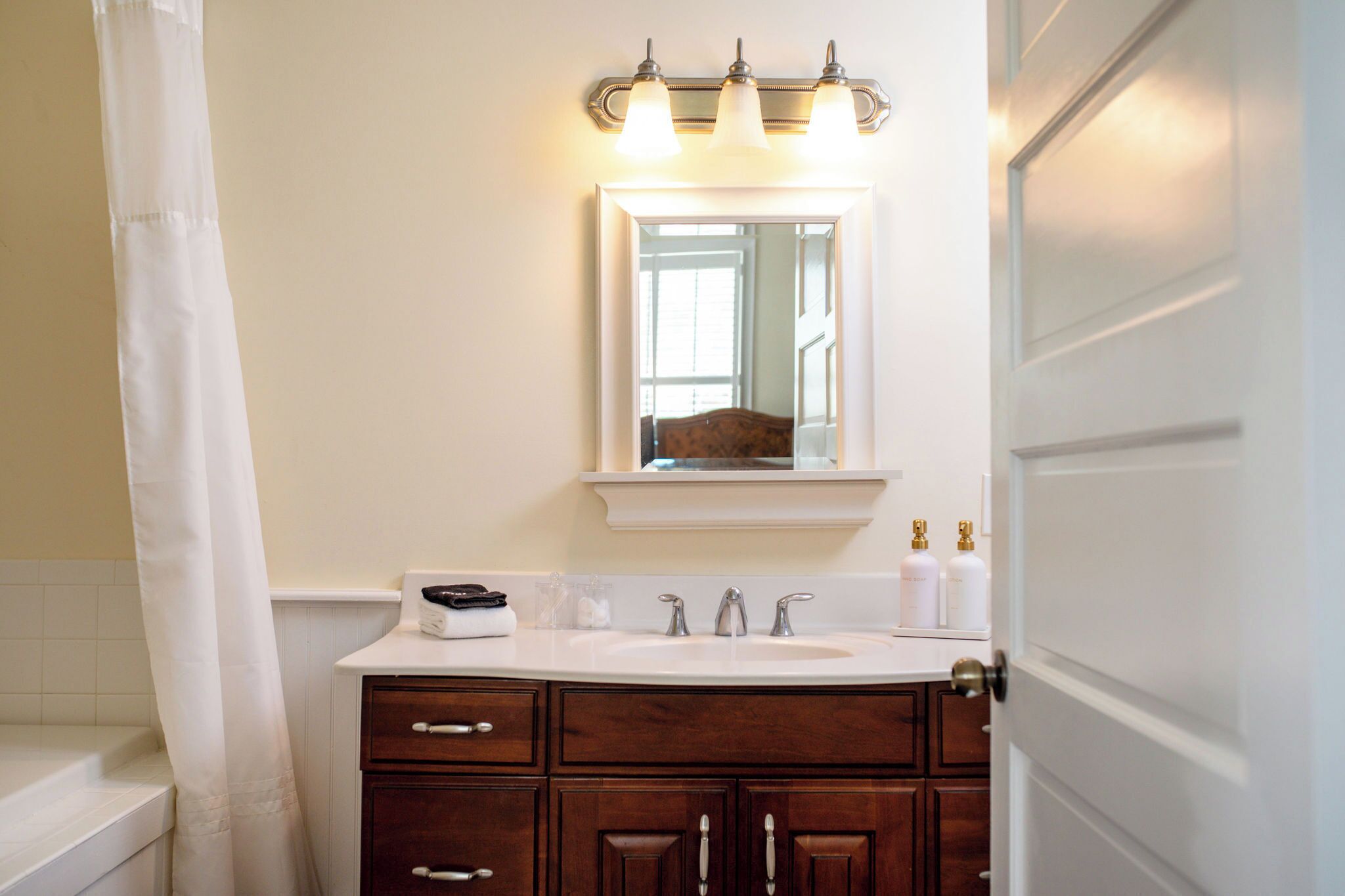 A bathroom with a white sink, a mirror, a towel, and a shower curtain.