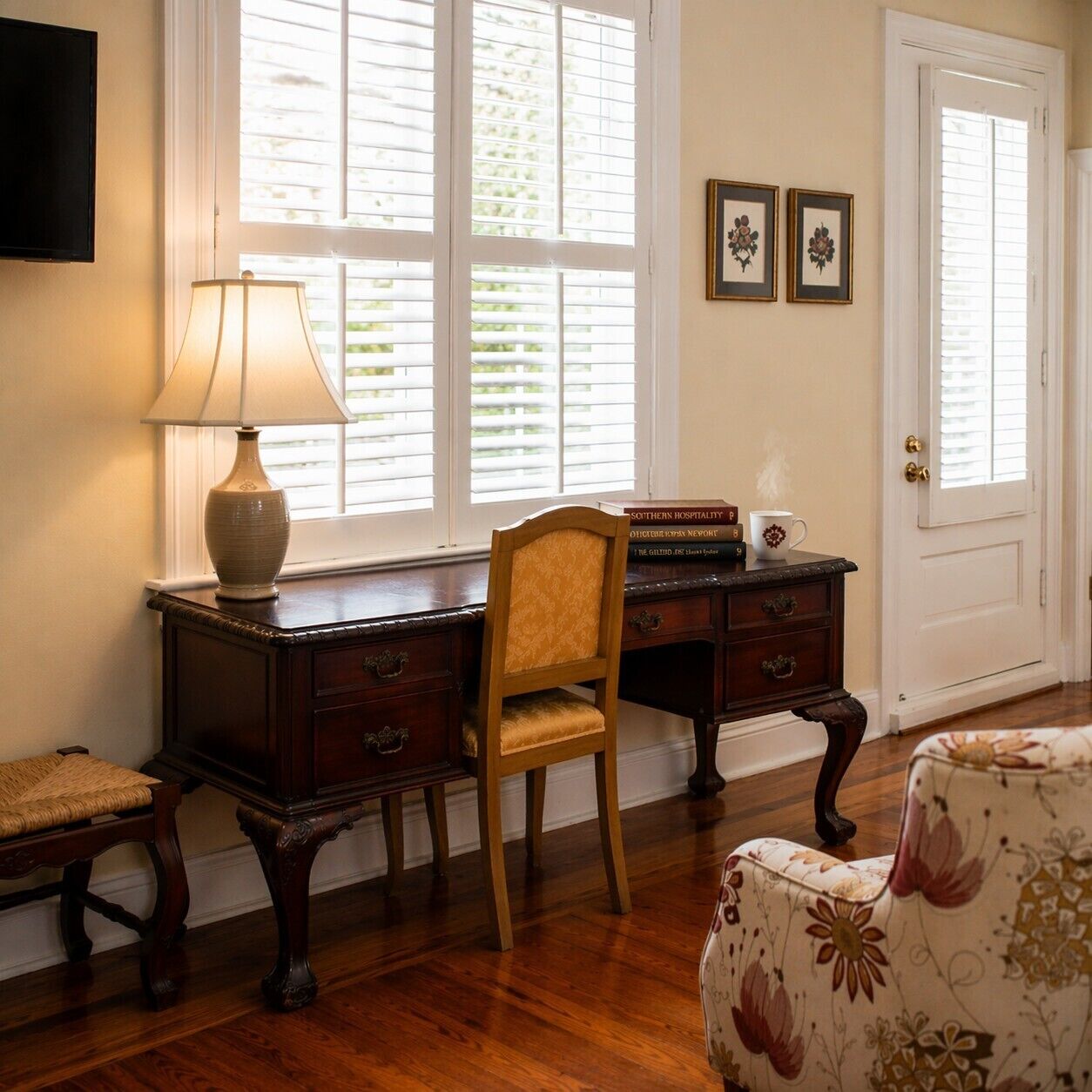 A room with a wooden desk, a chair, a lamp, a bookshelf, and a door.