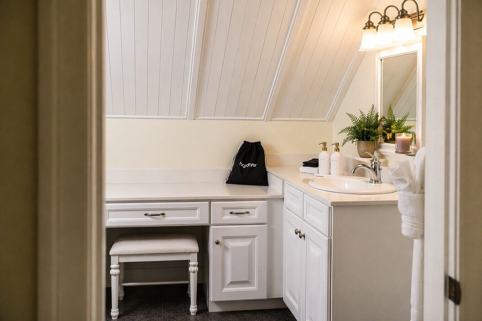 A bathroom with a vanity, sink, mirror, towel rack, and a small bench.
