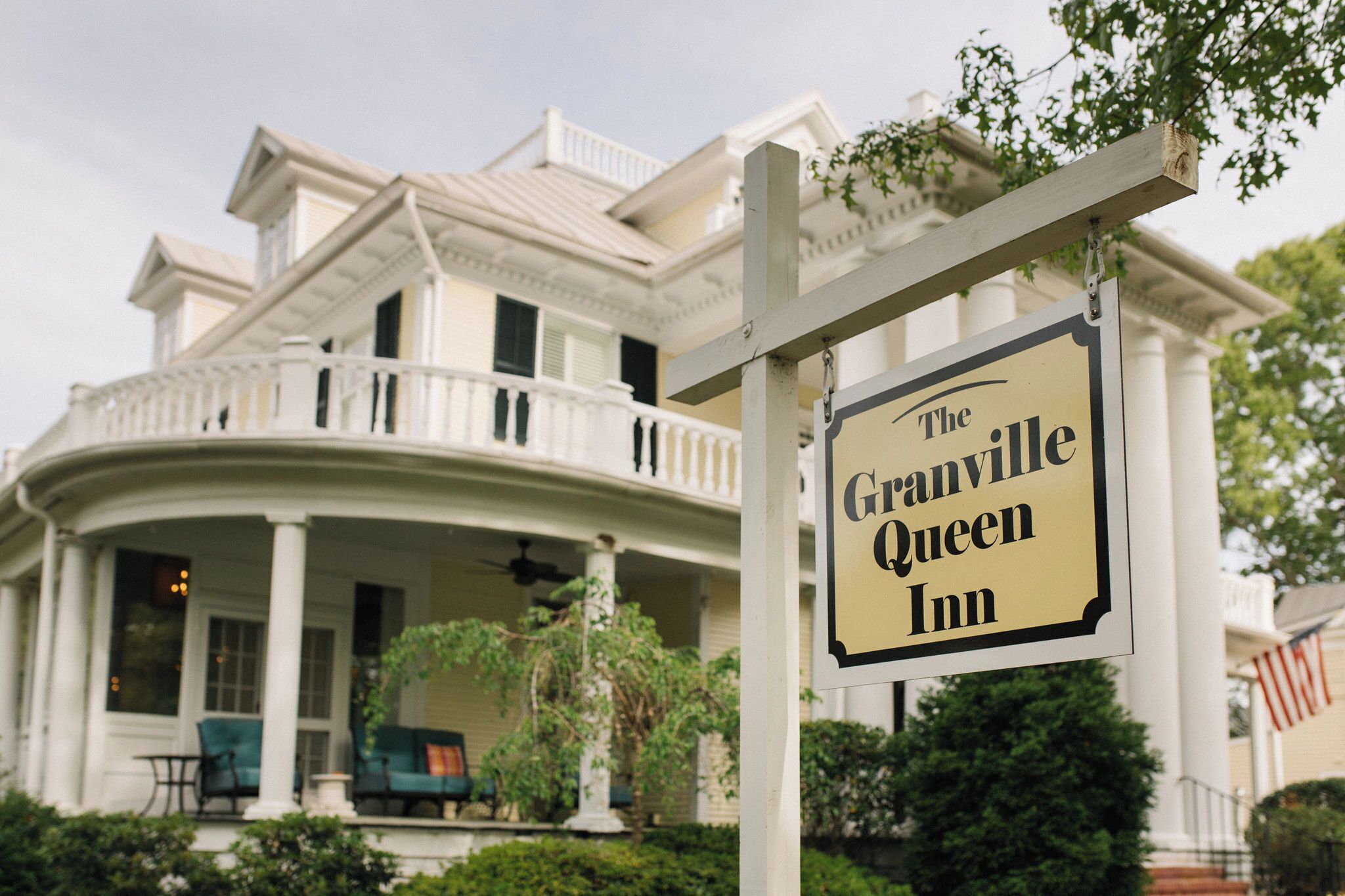 En stor, vit byggnad i kolonialstil med en veranda och en skylt som visar texten ”The Granville Queen Inn”.