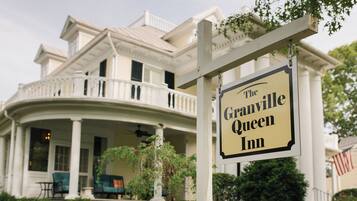 A large, white, colonial-style building with a porch and a sign that reads 'The Granville Queen Inn.'