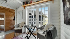 Une pièce chaleureuse avec deux fauteuils en osier, une petite table et une grande fenêtre à carreaux.