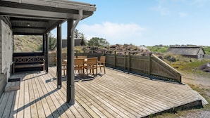 Une terrasse en bois avec des sièges extérieurs, un espace abrité et une vue sur le paysage environnant.