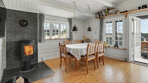Une pièce chaleureuse avec une cheminée, une table à manger en bois et de grandes fenêtres.