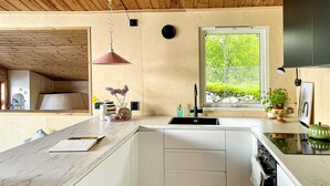 A modern kitchen with a marble countertop, a built-in sink, and a window with a view of greenery.