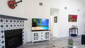 Ein Wohnzimmer mit Kamin, Fernseher und einer an der Wand befestigten Gitarre.