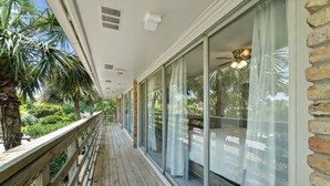A wooden deck with glass doors leading to a covered area, surrounded by greenery. - 2 bedroom, walk to the Beach! Sleeps 6, outdoor games and yard space! (Fort Walton Beach)