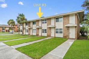 A row of three-story brick apartment buildings with a flat roof, each featuring a single door and windows. - 2 bedroom, walk to the Beach! Sleeps 6, outdoor games and yard space! (Fort Walton Beach)