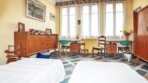 Ein Zimmer mit zwei Betten, einem Holzschrank, einem Schreibtisch mit Stühlen und einem Heizkörper.