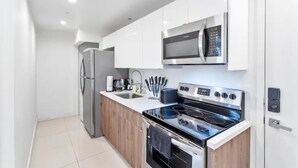 Une cuisine moderne avec des meubles blancs, un réfrigérateur en acier inoxydable, un four à micro-ondes et une cuisinière à gaz.