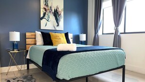Une chambre à coucher moderne avec un lit, deux tables de chevet, un tapis et un tableau au mur.
