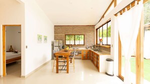 A spacious kitchen with a dining area, large windows, and a view of greenery outside. - Villa Akari - Modern and Sophisticated Villa close to the Beach (Puntarenas Province)