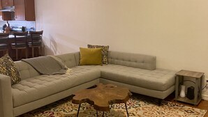 A living room with a sectional sofa, a coffee table, and a patterned rug.