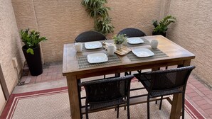 A wooden table set with white plates, cups, and a small potted plant.
