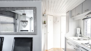 Een moderne keuken met witte kastjes, een kroonluchter en een eethoek met een tafel en stoelen.