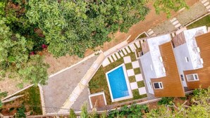 Eine Vogelperspektive auf ein modernes Haus mit Swimmingpool, umgeben von einem Garten und einem eingezäunten Bereich.