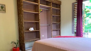 Una habitación con cama, un armario de madera, una planta en maceta y una ventana con cortinas.